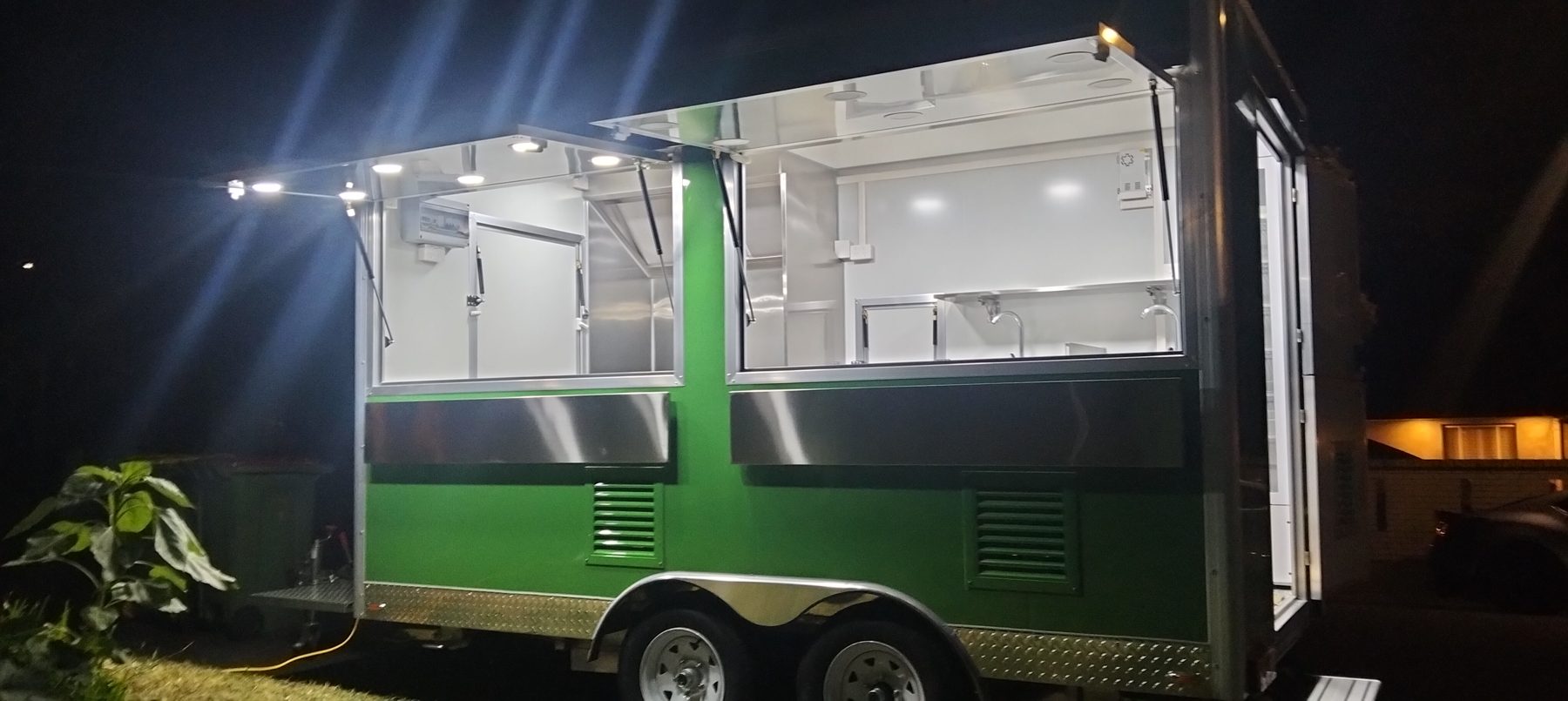 Green food trailer lit up at night